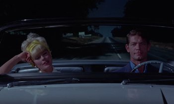 Movie still from “The Oscar” (1966), directed by Russell Rouse – A man and a woman sitting in the back seat of a car; Medium shot, Low angle