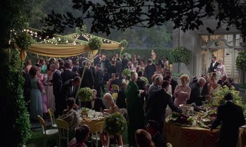 Movie still from “The Oscar” (1966), directed by Russell Rouse – A group of people standing around a table with food on it; Extreme Wide shot, High angle