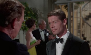 Movie still from “The Oscar” (1966), directed by Russell Rouse – A man in a tuxedo standing in front of other people; Close Up shot, Over the shoulder angle