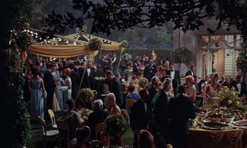 Movie still from “The Oscar” (1966), directed by Russell Rouse – A group of people standing around a table with food on it; Extreme Wide shot, High angle