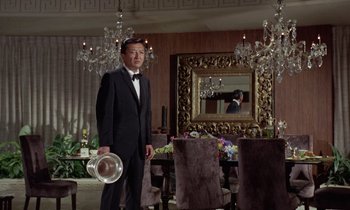 Movie still from “The Oscar” (1966), directed by Russell Rouse – A man in a tuxedo standing next to a dining room table; Medium shot, Low angle