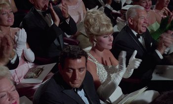 Movie still from “The Oscar” (1966), directed by Russell Rouse – A man and a woman sitting in front of each other in formal wear; Medium shot, Low angle