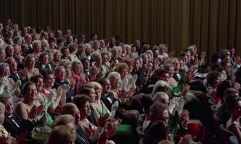 Movie still from “The Oscar” (1966), directed by Russell Rouse – A large group of people sitting in a room clapping and applauding; Extreme Wide shot, High angle
