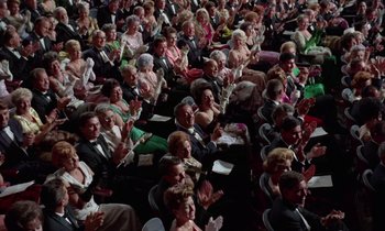 Movie still from “The Oscar” (1966), directed by Russell Rouse – A large group of people sitting in a room clapping; Extreme Wide shot, High angle