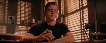Movie still from “The Outsiders” (1983), directed by Francis Ford Coppola – A young man writing on top of a paper; Close Up shot, Low angle