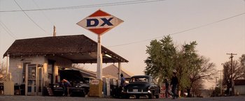 Movie still from “The Outsiders” (1983), directed by Francis Ford Coppola – An old truck parked next to a gas station sign; Extreme Wide shot, Low angle
