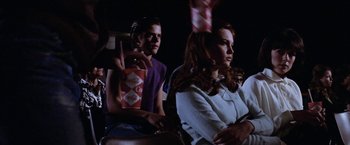 Movie still from “The Outsiders” (1983), directed by Francis Ford Coppola – A couple of people sitting next to each other at a movie; Medium shot, Over the shoulder angle
