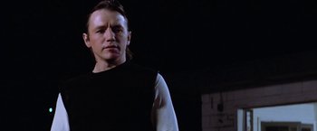 Movie still from “The Outsiders” (1983), directed by Francis Ford Coppola – A man standing in a dark room with his arms crossed; Close Up shot, Low angle