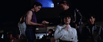Movie still from “The Outsiders” (1983), directed by Francis Ford Coppola – A group of young people standing around each other in a room; Medium shot, Over the shoulder angle