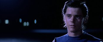 Movie still from “The Outsiders” (1983), directed by Francis Ford Coppola – A young man in a blue shirt is looking at the camera; Close Up shot, Low angle