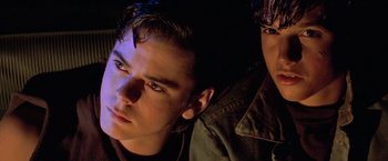 Movie still from “The Outsiders” (1983), directed by Francis Ford Coppola – Two young men sitting next to each other in the dark; Close Up shot, Low angle