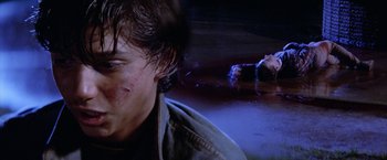 Movie still from “The Outsiders” (1983), directed by Francis Ford Coppola – A man in a blue shirt is in a body of water; Close Up shot, High angle