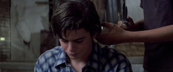 Movie still from “The Outsiders” (1983), directed by Francis Ford Coppola – A young man getting his hair combed by a stylist; Close Up shot, Over the shoulder angle