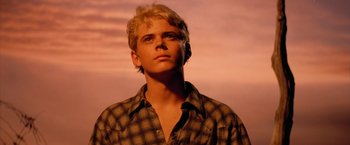 Movie still from “The Outsiders” (1983), directed by Francis Ford Coppola – A man with blonde hair and a checkered shirt looking to his left; Close Up shot, Low angle