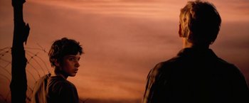 Movie still from “The Outsiders” (1983), directed by Francis Ford Coppola – A man standing next to another man on a beach; Close Up shot, Over the shoulder angle