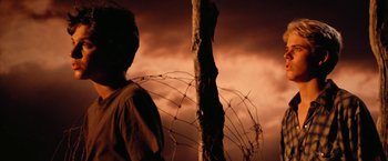 Movie still from “The Outsiders” (1983), directed by Francis Ford Coppola – A man standing next to a tree with barbed wire on it; Medium shot, Low angle