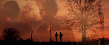 Movie still from “The Outsiders” (1983), directed by Francis Ford Coppola – Two people standing in front of an image of a man; Medium shot, Low angle