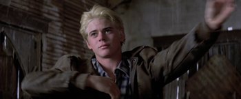 Movie still from “The Outsiders” (1983), directed by Francis Ford Coppola – A man with blonde hair and a plaid shirt; Close Up shot, Low angle