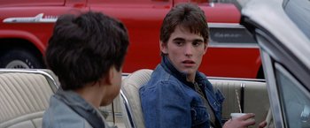 Movie still from “The Outsiders” (1983), directed by Francis Ford Coppola – Two young men sitting in the back seat of a car; Close Up shot, Over the shoulder angle