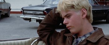 Movie still from “The Outsiders” (1983), directed by Francis Ford Coppola – A young man sitting on the side of the road; Close Up shot, Low angle