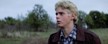 Movie still from “The Outsiders” (1983), directed by Francis Ford Coppola – A young man with blonde hair and a plaid shirt; Close Up shot, Low angle