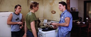 Movie still from “The Outsiders” (1983), directed by Francis Ford Coppola – Two young men are standing in front of an oven; Medium shot, Over the shoulder angle
