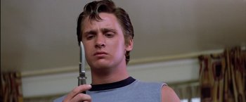 Movie still from “The Outsiders” (1983), directed by Francis Ford Coppola – A young man holding a knife in his hand; Close Up shot, Low angle