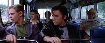 Movie still from “The Outsiders” (1983), directed by Francis Ford Coppola – A man sitting on a bus next to other people; Medium shot, Over the shoulder angle