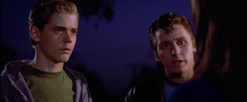 Movie still from “The Outsiders” (1983), directed by Francis Ford Coppola – A couple of men standing next to each other in front of trees; Close Up shot, Low angle