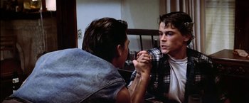 Movie still from “The Outsiders” (1983), directed by Francis Ford Coppola – Two young men arm wrestling while sitting at a table; Close Up shot, Over the shoulder angle