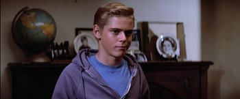 Movie still from “The Outsiders” (1983), directed by Francis Ford Coppola – A young man in a blue shirt and purple hoodie; Close Up shot, Over the shoulder angle