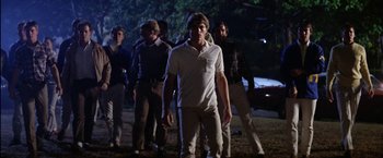 Movie still from “The Outsiders” (1983), directed by Francis Ford Coppola – A group of young men standing on top of a grass covered field; Medium shot, Low angle