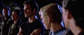 Movie still from “The Outsiders” (1983), directed by Francis Ford Coppola – A man standing next to another man in a dark room; Close Up shot, Over the shoulder angle