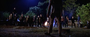 Movie still from “The Outsiders” (1983), directed by Francis Ford Coppola – A group of people standing around a fire at night; Wide shot, High angle