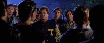 Movie still from “The Outsiders” (1983), directed by Francis Ford Coppola – A group of men standing next to each other in front of trees; Medium shot, Over the shoulder angle