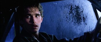 Movie still from “The Outsiders” (1983), directed by Francis Ford Coppola – A young man sitting in the driver's seat of a car; Close Up shot, Low angle