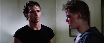 Movie still from “The Outsiders” (1983), directed by Francis Ford Coppola – A man standing next to another man in a room; Close Up shot, Over the shoulder angle