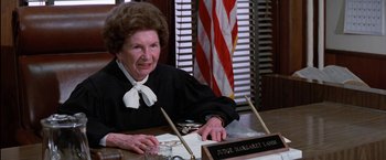 Movie still from “The Outsiders” (1983), directed by Francis Ford Coppola – An older woman sitting at a table in a courtroom; Close Up shot, High angle
