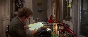 Movie still from “The Owl and the Pussycat” (1970), directed by Herbert Ross – A person is reading a book in a room; Medium shot, High angle