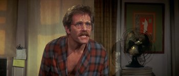 Movie still from “The Owl and the Pussycat” (1970), directed by Herbert Ross – An older man wearing a plaid shirt and glasses; Medium shot, Over the shoulder angle
