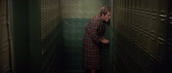 Movie still from “The Owl and the Pussycat” (1970), directed by Herbert Ross – A man wearing a plaid shirt is leaning against a door; Medium shot, Low angle