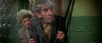Movie still from “The Owl and the Pussycat” (1970), directed by Herbert Ross – An older man holding an umbrella in a room; Medium shot, Low angle
