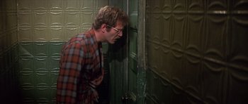 Movie still from “The Owl and the Pussycat” (1970), directed by Herbert Ross – A man with glasses is leaning against a door; Medium shot, Low angle