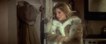 Movie still from “The Owl and the Pussycat” (1970), directed by Herbert Ross – A woman in a fur coat leaning against a door; Medium shot, High angle