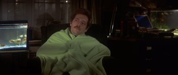 Movie still from “The Owl and the Pussycat” (1970), directed by Herbert Ross – A man wrapped in a blanket sitting in a chair; Medium shot, High angle