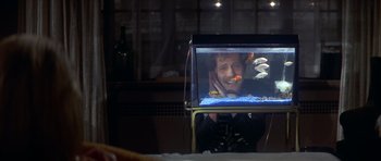 Movie still from “The Owl and the Pussycat” (1970), directed by Herbert Ross – A man sitting in front of a fish tank; Medium shot, High angle