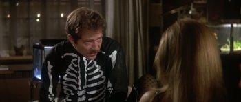 Movie still from “The Owl and the Pussycat” (1970), directed by Herbert Ross – A man in a skeleton costume sitting next to a woman; Medium shot, Over the shoulder angle