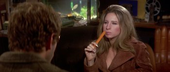 Movie still from “The Owl and the Pussycat” (1970), directed by Herbert Ross – A woman holding a carrot in her mouth while sitting next to a man; Close Up shot, Over the shoulder angle