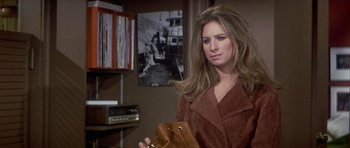 Movie still from “The Owl and the Pussycat” (1970), directed by Herbert Ross – A woman holding a brown purse in a room; Medium shot, Over the shoulder angle