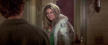 Movie still from “The Owl and the Pussycat” (1970), directed by Herbert Ross – A woman wearing a green dress and a fur coat; Medium shot, Over the shoulder angle